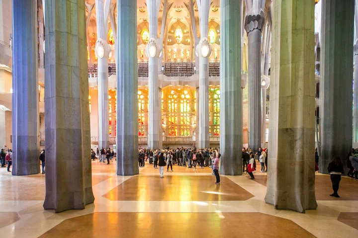 Visitors among the tall columns of the nave, with warm light from the windows beyond
