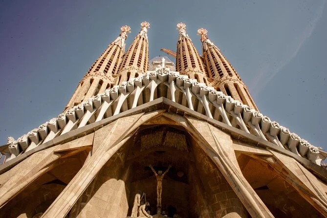 Looking up at the Passion facade and its four spires against a blue sky