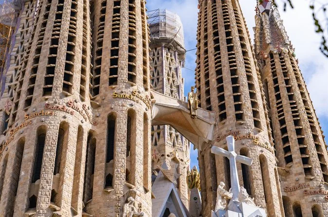 Close-up of the Sagrada Familia spires with carved lettering and a white cross