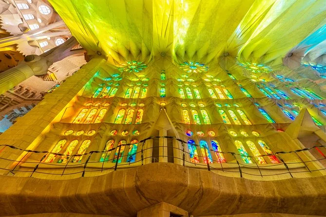Yellow, green and blue light from stained glass washing over the vaults above a gallery